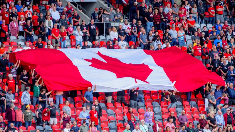 Fans at a REDBLACKS game holding a Canada Flag
